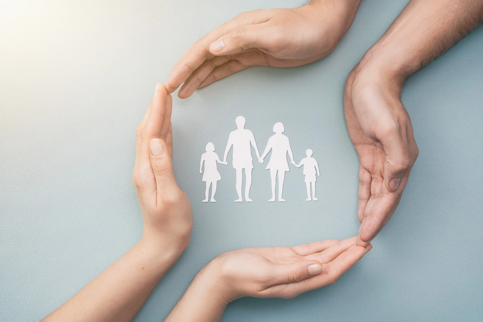 Hands Holding A Paper Cutout Of A Family